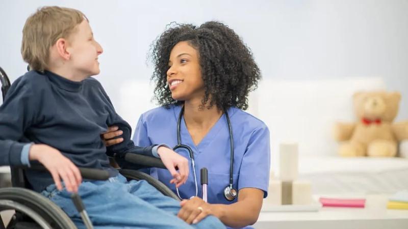 Female doctor helps boy in wheelchair