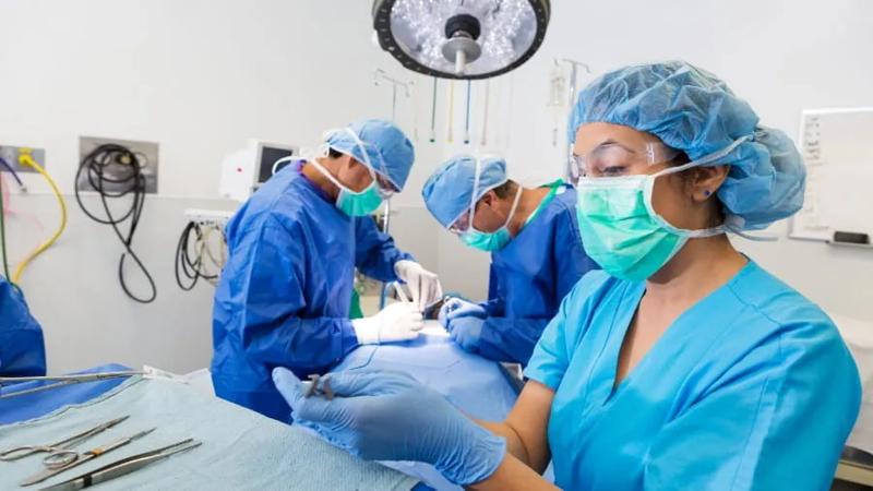 A surgical technician skillfully assisting doctors performing surgery on a patient.