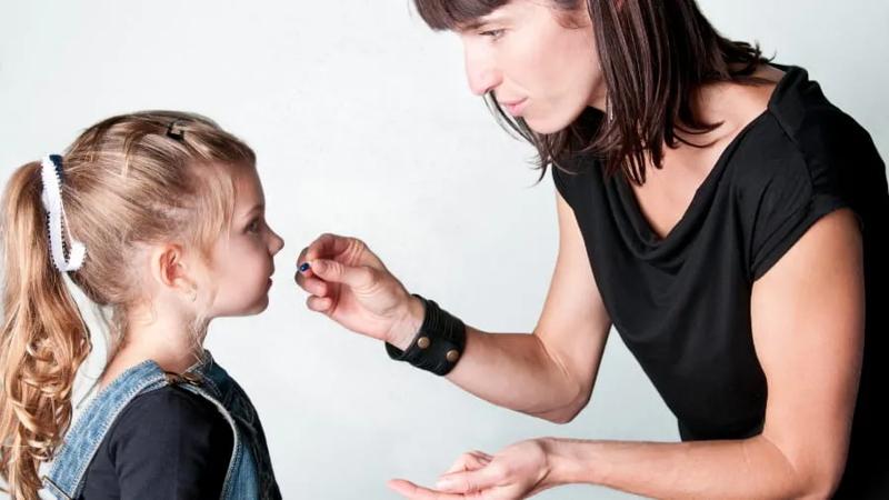 Mother giving child a pill.