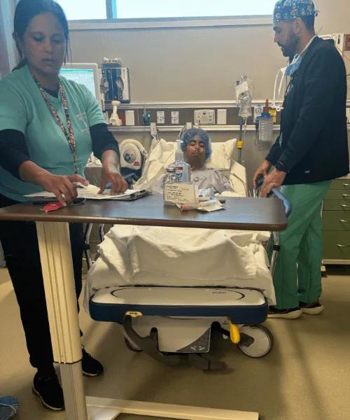 Boy in hospital bed next to 2 doctors