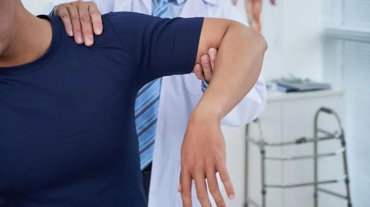 Physician examining male patients shoulder