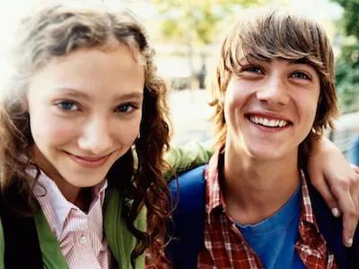 Teenage Girl Stands Smiling With Her Arm Around Her Friend