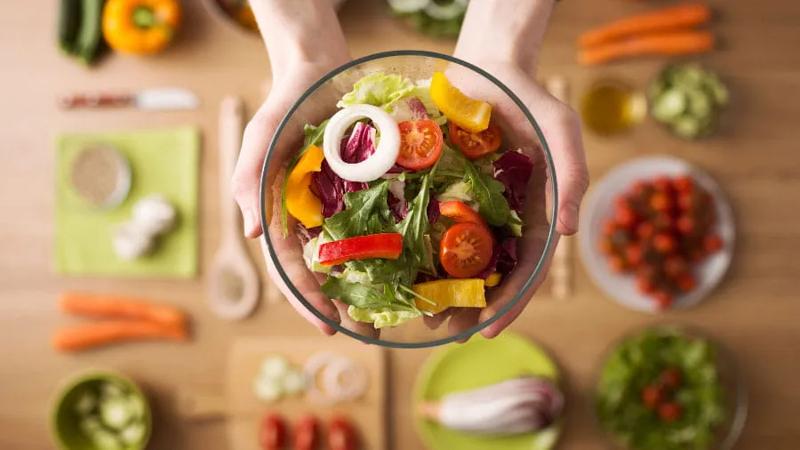 Hands holding a brightly colored salad