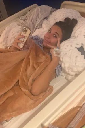 Lady laying in hospital bed showing the peace sign